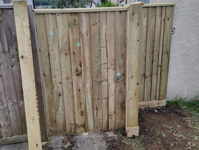 Custom wooden gate installation in Plymouth featuring new timber gate, posts and metal latch.
